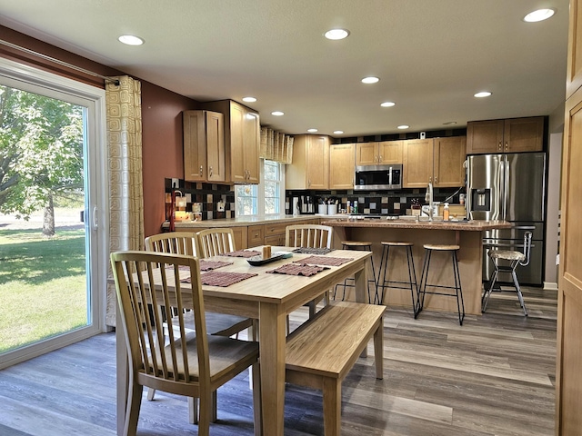 kitchen featuring a kitchen breakfast bar, tasteful backsplash, stainless steel appliances, and light hardwood / wood-style floors