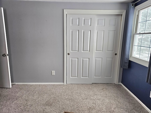 unfurnished bedroom featuring carpet flooring, multiple windows, and a closet