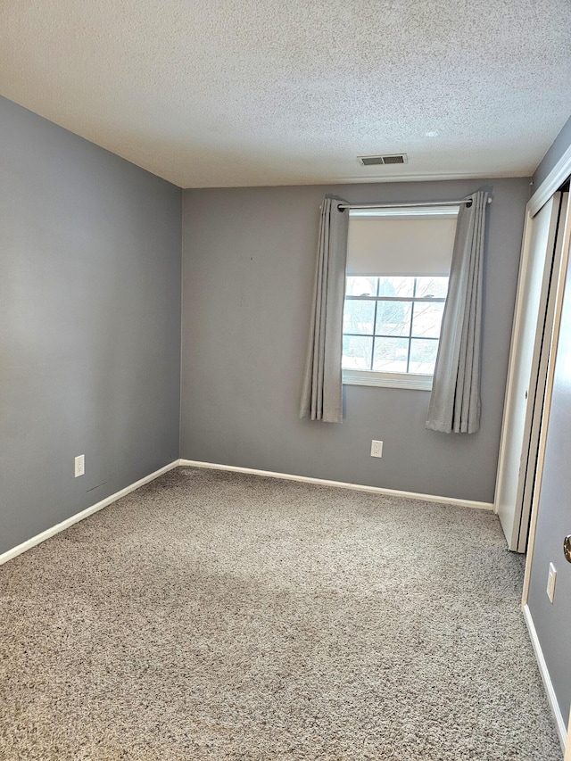 carpeted empty room featuring a textured ceiling