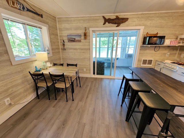 dining space featuring light hardwood / wood-style floors, plenty of natural light, and wood walls