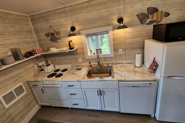 kitchen featuring white cabinets, white appliances, light stone counters, and sink