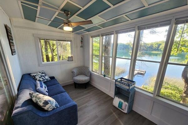 sunroom featuring plenty of natural light, ceiling fan, and a water view