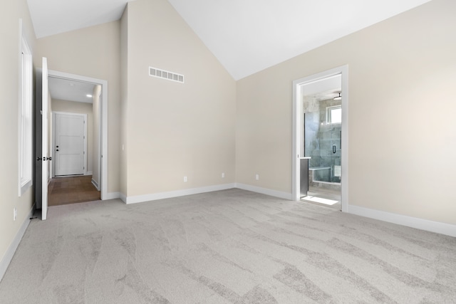 carpeted empty room with high vaulted ceiling