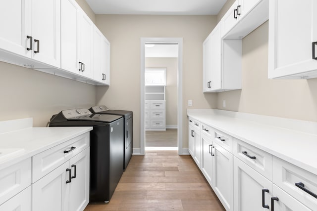 washroom with cabinets, light hardwood / wood-style flooring, and washing machine and clothes dryer