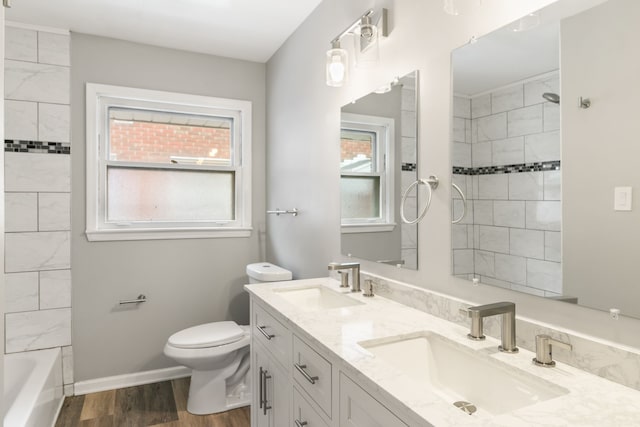 full bathroom featuring hardwood / wood-style floors, vanity, tiled shower / bath combo, and toilet