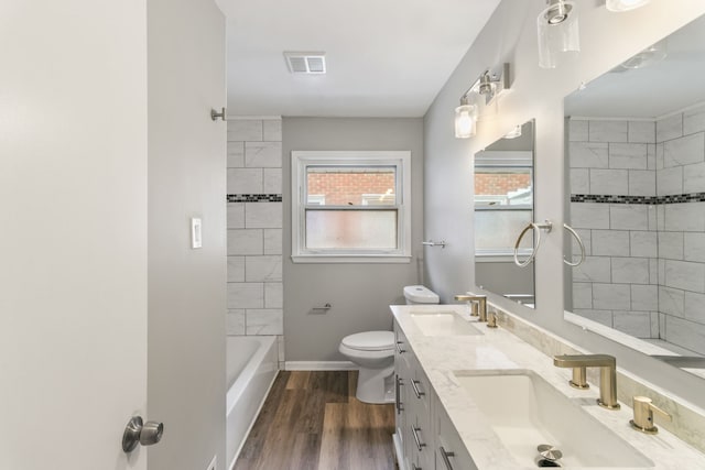 full bathroom with hardwood / wood-style floors, vanity, toilet, and tiled shower / bath combo