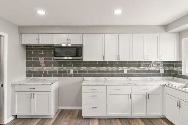 kitchen with tasteful backsplash, white cabinets, and wood-type flooring