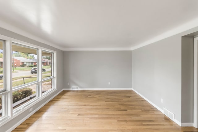 empty room with light hardwood / wood-style floors and ornamental molding