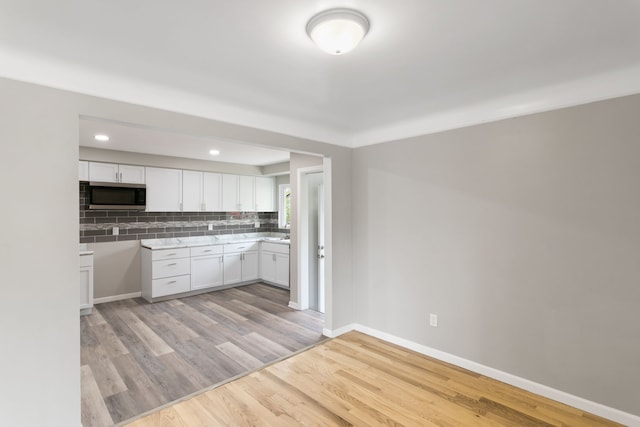 kitchen with white cabinets, backsplash, and light hardwood / wood-style flooring