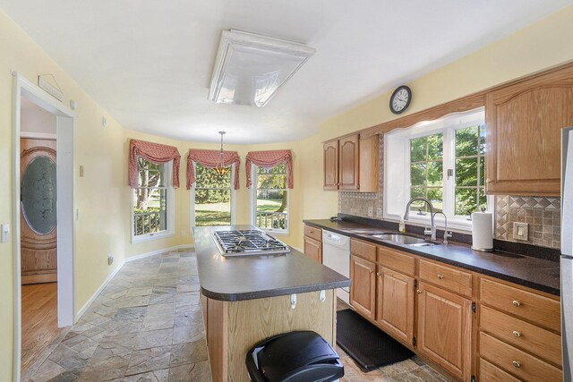 507 Lena Dr, South Haven, MI 49090 - kitchen featuring stone tile flooring, white dishwasher, a sink, baseboards, and decorative backsplash