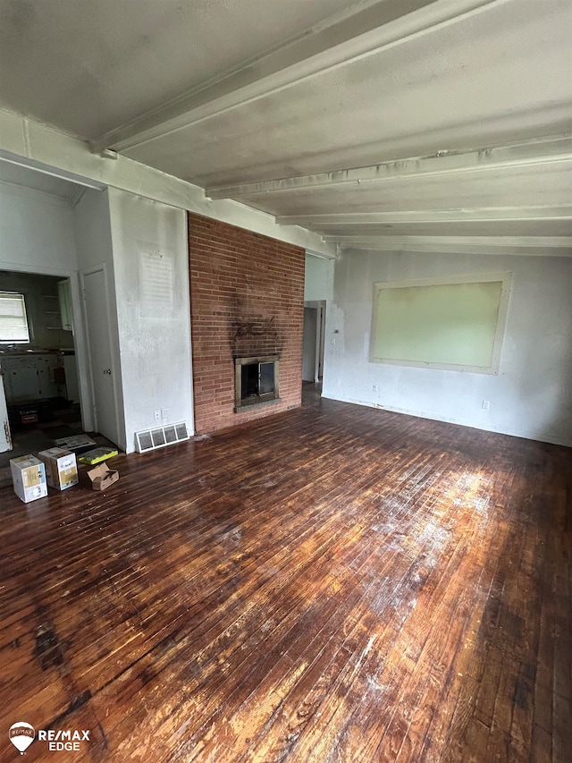 unfurnished living room with beamed ceiling, dark wood-type flooring, and a brick fireplace