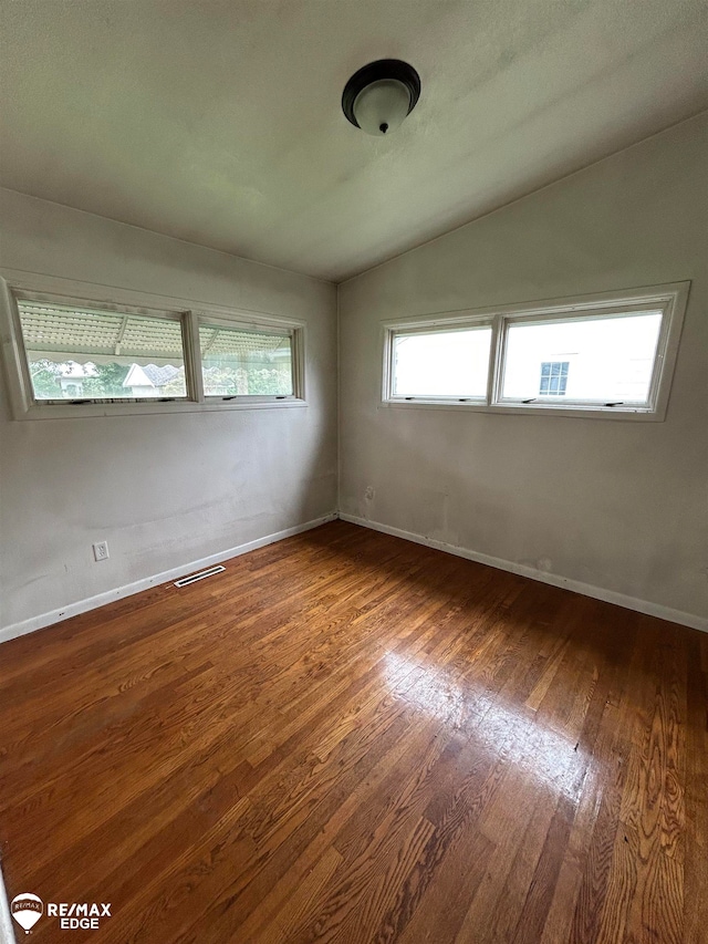 spare room with dark hardwood / wood-style flooring and vaulted ceiling