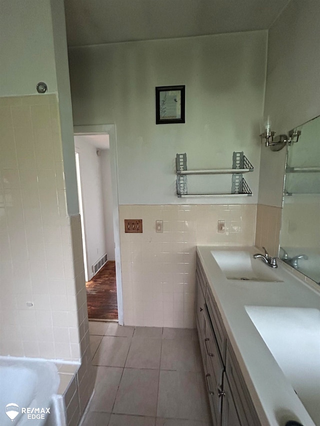 bathroom with tile patterned flooring, vanity, tile walls, and a bathing tub