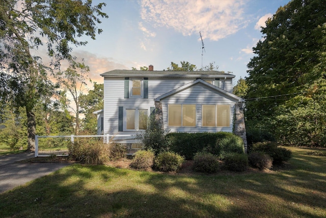 property exterior at dusk featuring a lawn