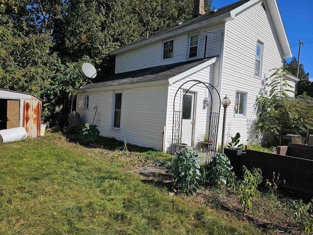 rear view of house with a yard and a shed