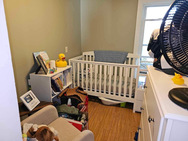 bedroom with multiple windows, a crib, and light wood-type flooring