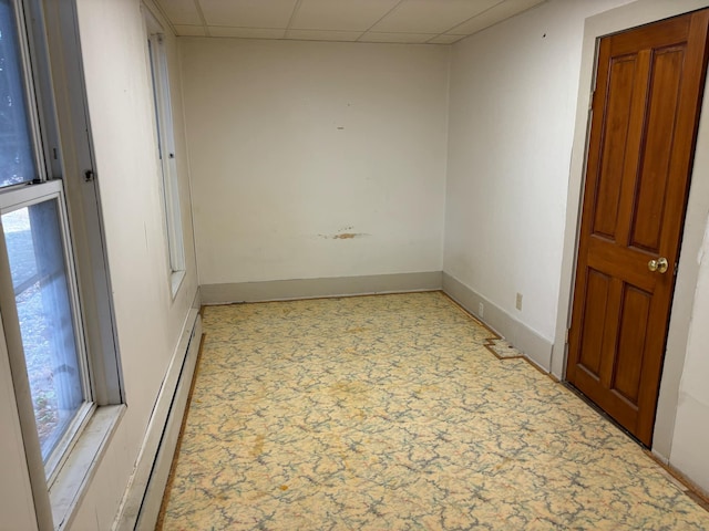 unfurnished room featuring a drop ceiling and a baseboard heating unit