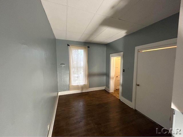 interior space with a drop ceiling and dark hardwood / wood-style floors