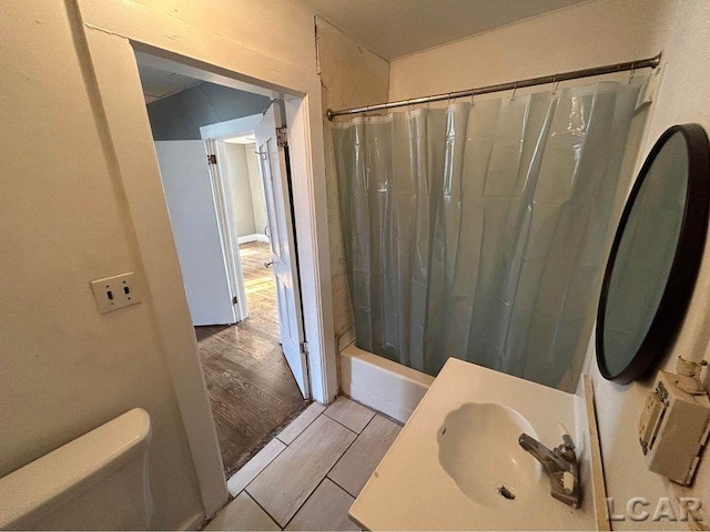 full bathroom with hardwood / wood-style flooring, shower / bath combination with curtain, toilet, and sink