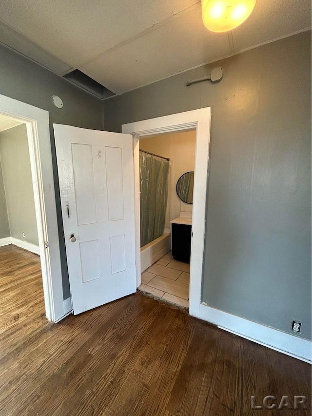 unfurnished bedroom featuring wood-type flooring and ensuite bath