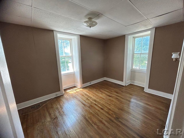 unfurnished room with a paneled ceiling and dark hardwood / wood-style floors