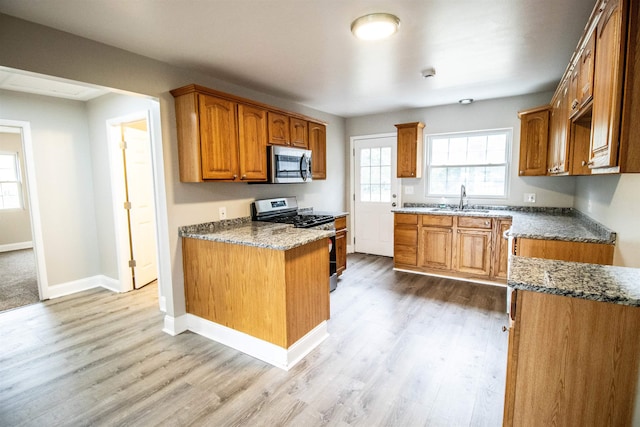 7029 Silver Lake Rd, Linden, MI 48451 - kitchen with appliances with stainless steel finishes, light wood finished floors, brown cabinetry, and dark stone countertops