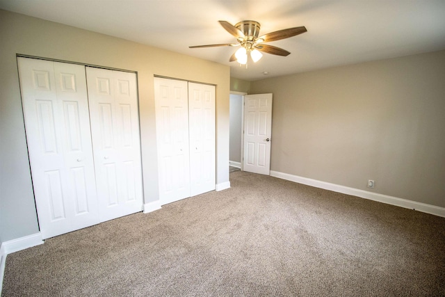 unfurnished bedroom featuring carpet flooring, two closets, and ceiling fan