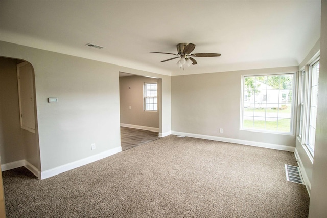 empty room with ceiling fan and dark carpet