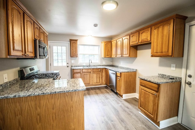 7029 Silver Lake Rd, Linden, MI 48451 - kitchen with appliances with stainless steel finishes, light wood-style floors, light stone counters, and brown cabinets