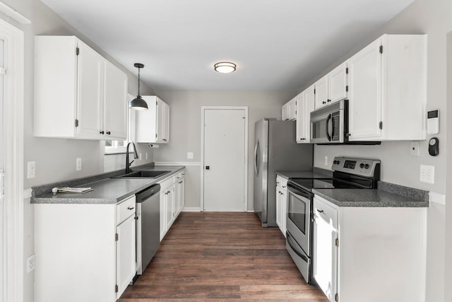 kitchen with dark hardwood / wood-style flooring, stainless steel appliances, sink, white cabinetry, and hanging light fixtures