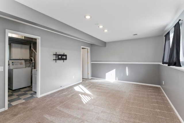 spare room featuring light carpet and washer / dryer