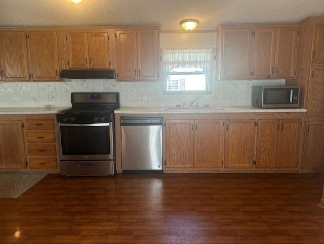 kitchen featuring sink, dark hardwood / wood-style flooring, stainless steel appliances, and a textured ceiling