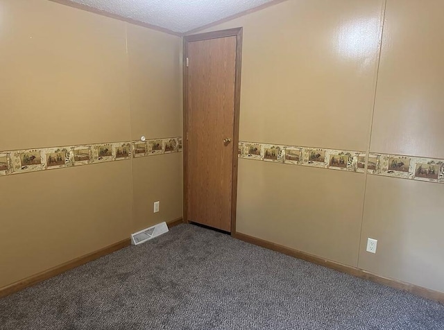 spare room with dark carpet, a textured ceiling, and vaulted ceiling