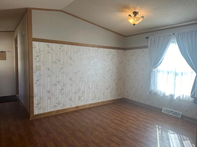 empty room with wood-type flooring, lofted ceiling, and a textured ceiling