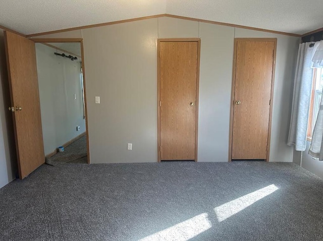 unfurnished bedroom with carpet flooring, lofted ceiling, and a textured ceiling