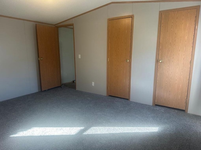 unfurnished bedroom with carpet flooring and lofted ceiling