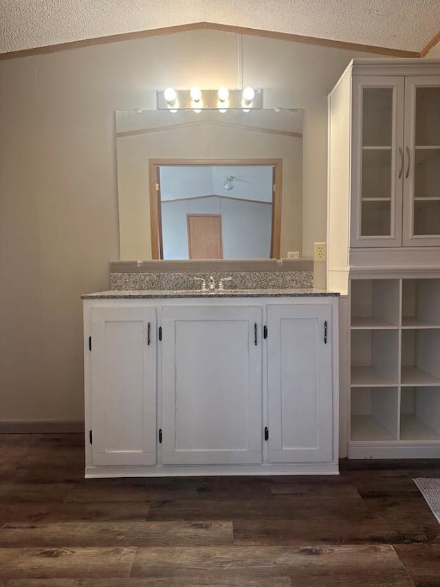 bathroom with wood-type flooring, vanity, a textured ceiling, and lofted ceiling