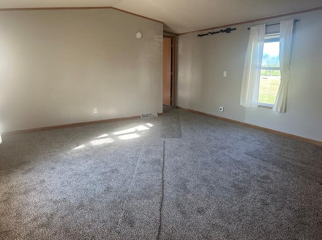 carpeted empty room featuring vaulted ceiling