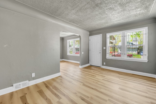 unfurnished room with light hardwood / wood-style flooring, a healthy amount of sunlight, and a textured ceiling