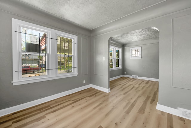 spare room featuring light hardwood / wood-style flooring and a textured ceiling