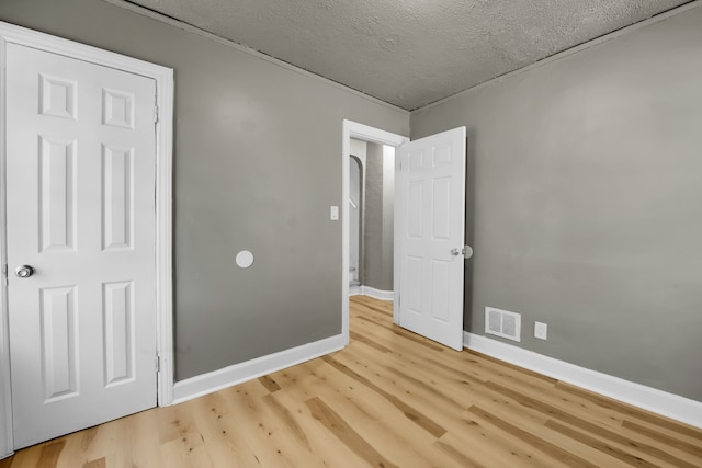 unfurnished bedroom with light hardwood / wood-style floors and a textured ceiling