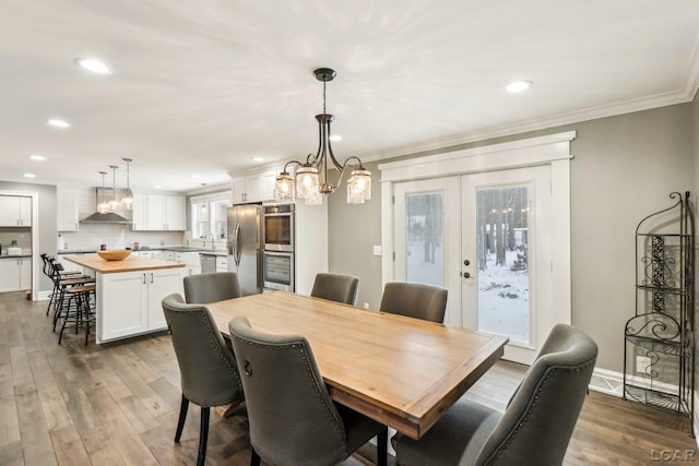 dining area featuring hardwood / wood-style floors, crown molding, a wealth of natural light, and french doors