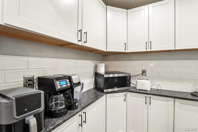 kitchen featuring backsplash, dark stone countertops, and white cabinets