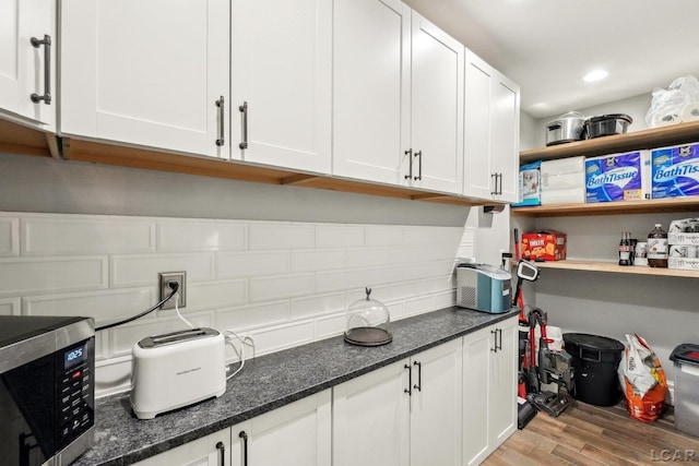 kitchen featuring dark stone counters, white cabinets, and light wood-type flooring