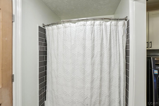 bathroom with washer / dryer and a textured ceiling