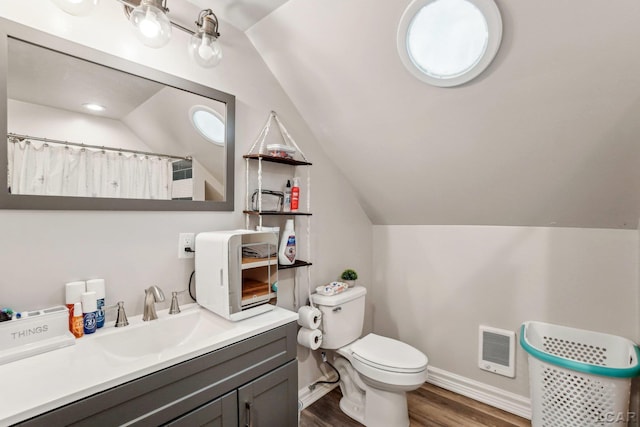 bathroom featuring hardwood / wood-style flooring, vanity, toilet, and vaulted ceiling