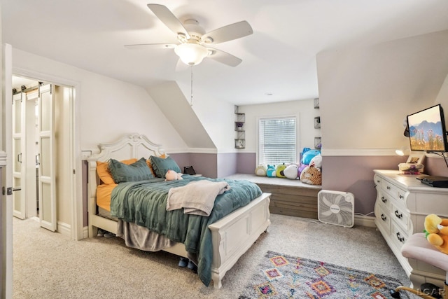 carpeted bedroom featuring a barn door and ceiling fan