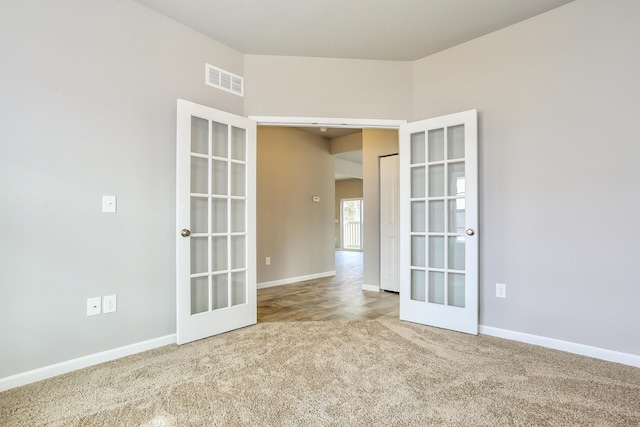 carpeted spare room featuring french doors