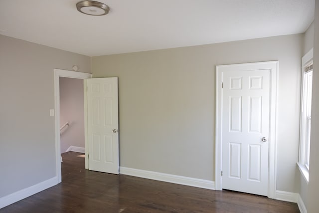 unfurnished bedroom with a closet, multiple windows, and dark wood-type flooring