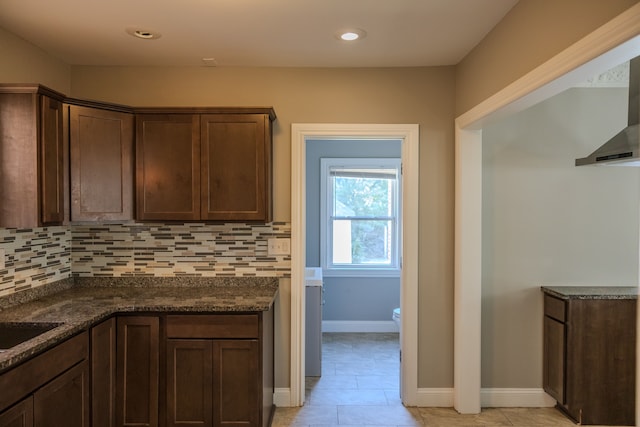 kitchen featuring backsplash, dark brown cabinetry, light tile patterned flooring, and dark stone counters